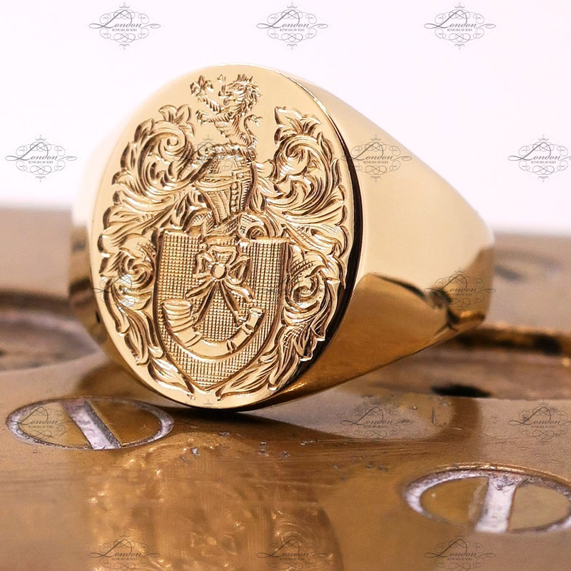 Yellow gold signet ring hand engraved with a surface Coat of Arms, sitting on engraver clamps