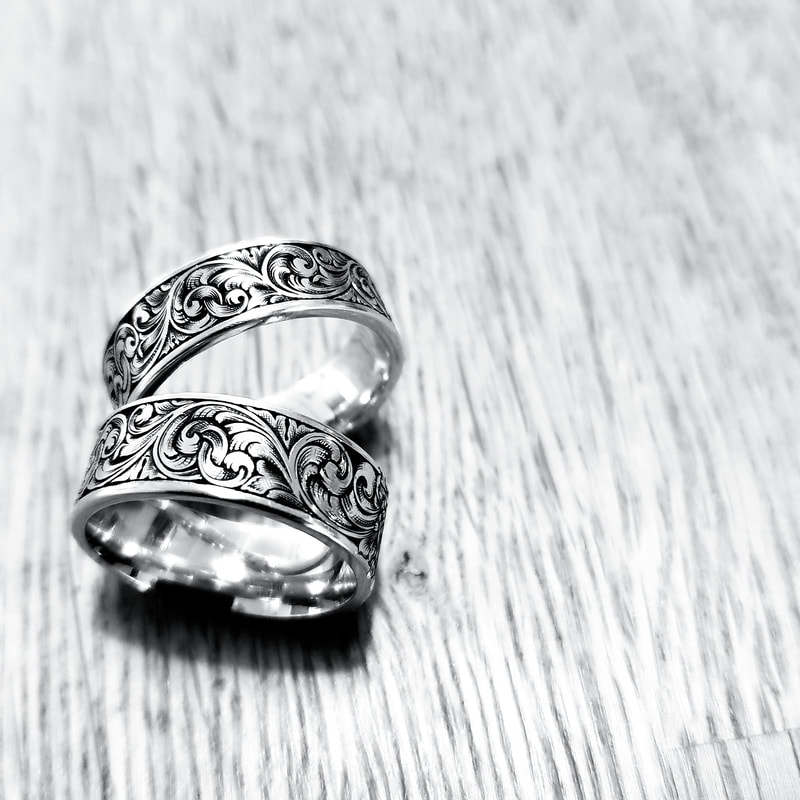 A pair of matching wedding rings with hand engraved scrollwork