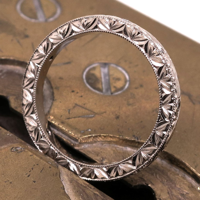 Hand engraved patternwork on the thickness of an 18ct white gold ladies wedding ring